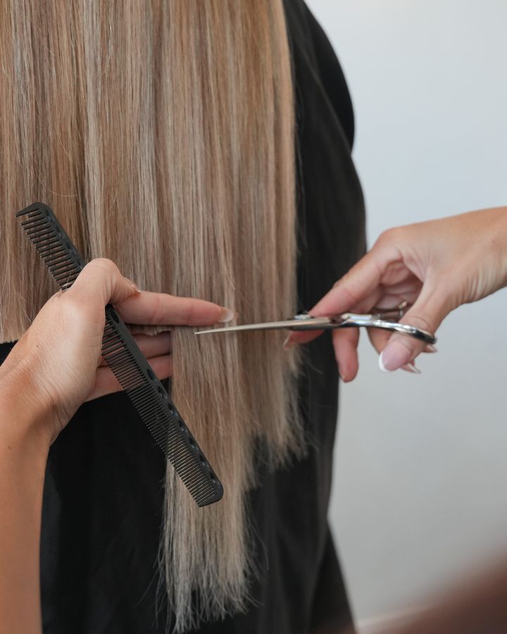 Stylist cutting the clip-in set into the client's hair