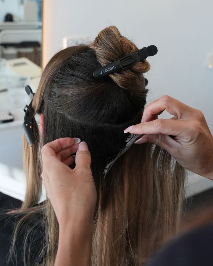 Stylist placing a clip-in weft into sectioned hair