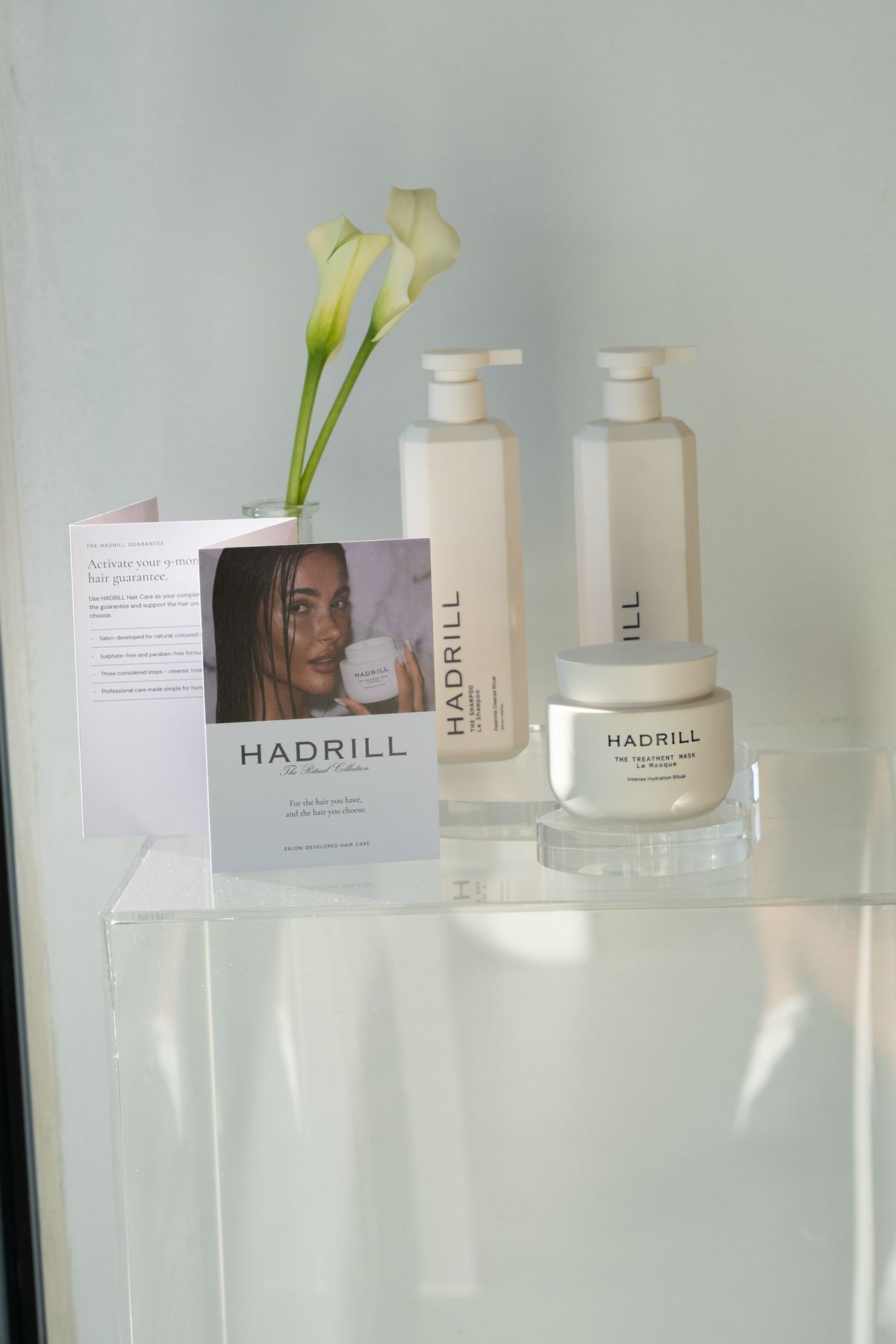 Hadrill Hair Care shampoo, conditioner and treatment mask displayed on an acrylic shelf in an EH salon