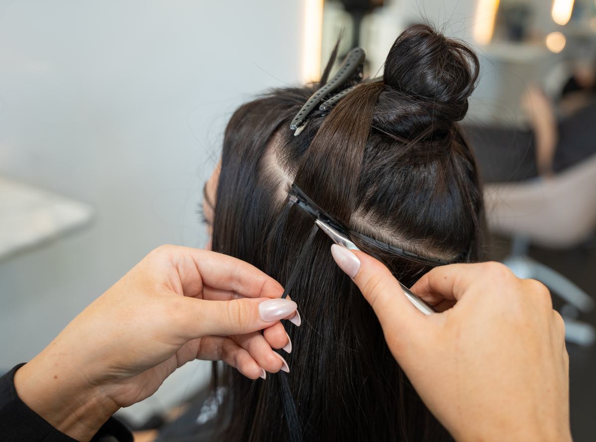 A Signature Weft being fitted close to the scalp on Emilee Hembrow's dark hair at an EH salon